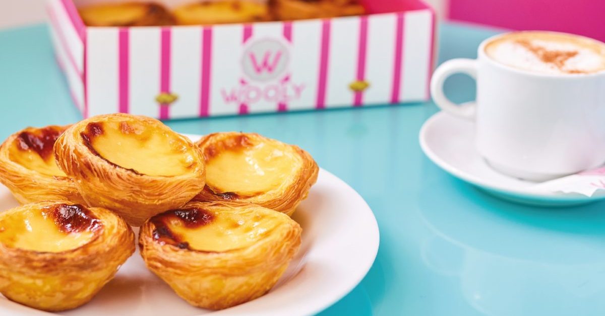 Wooly pastéis de nata op een bord met de gestreepte doos en koffie