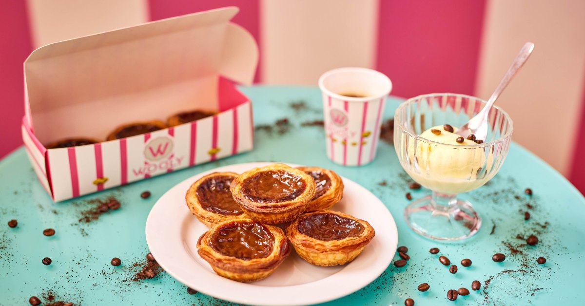 Wooly pastéis de nata op een bord, naast een koffie